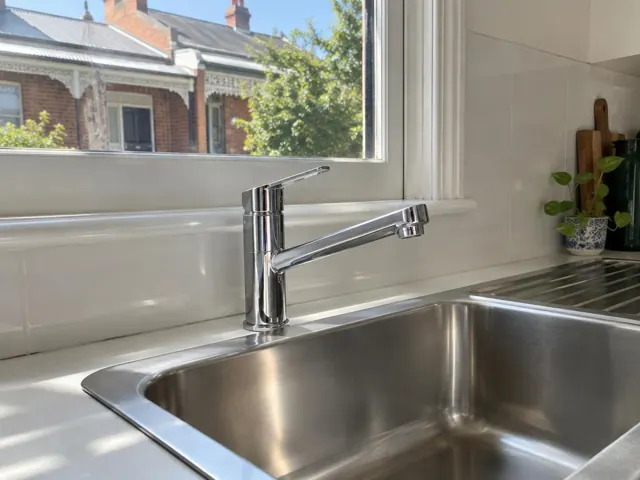 Chrome kitchen mixer tap beside a stainless sink and tiled splashback in a home kitchen in Crows Nest